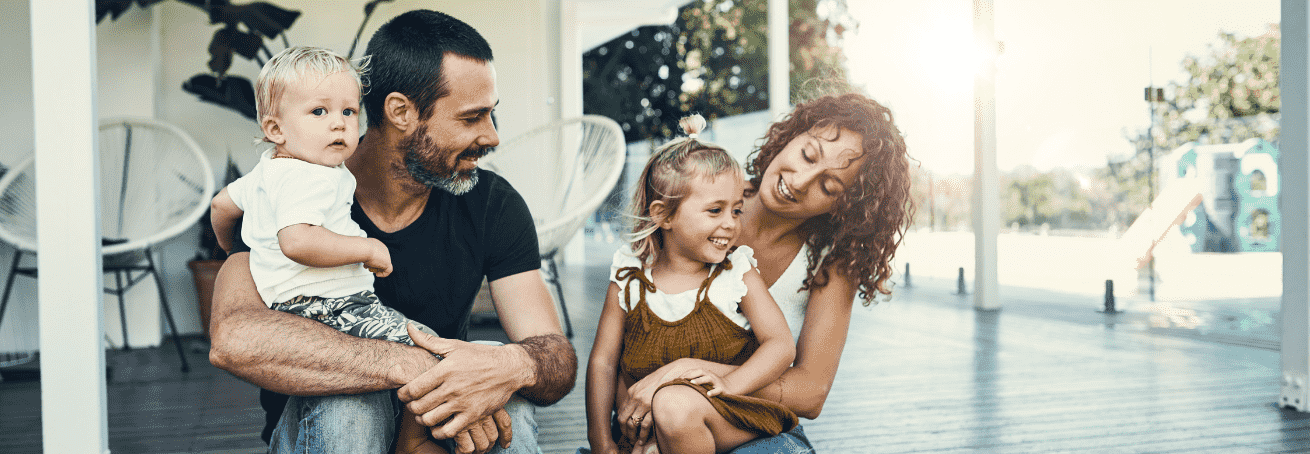 A couple sitting outside holding their two children.
